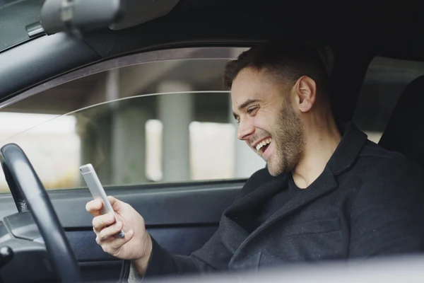 Rideshare driver smiling at phone with Beem Cash Advance
