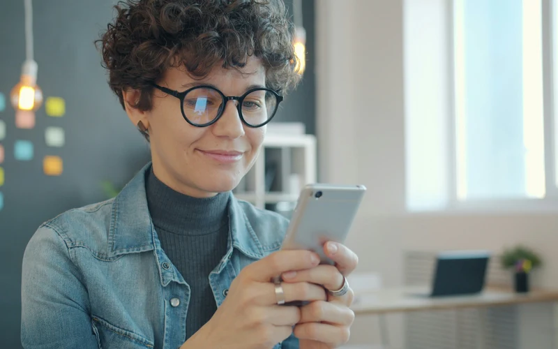 Person smiling while checking Beem Cash Advance on phone
